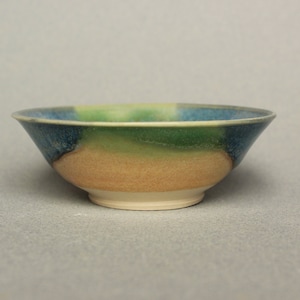 May include: A small, ceramic bowl with a blue, green and orange glaze. The bowl is slightly wider at the top than the bottom.