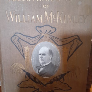 May include: A brown book with gold lettering on the cover. The title is "Illustrious Life of William McKinley, Our Twenty-Fifth President". The cover features a portrait of William McKinley in an oval frame.