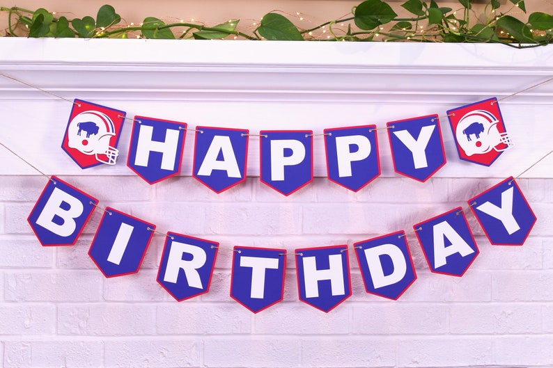 May include: A blue and red banner with the words "Happy Birthday" in white letters. The banner has a football helmet with a buffalo silhouette on each end.
