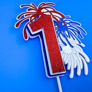 May include: Red, white, and blue glitter paper cutout of the number one with firework designs.