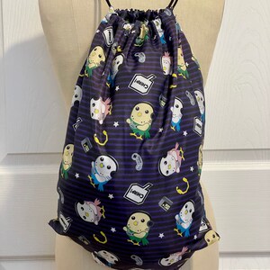 May include: A black drawstring bag with a purple and white striped pattern. The bag features a repeating design of cartoon birds wearing headphones and holding video game controllers. The text "Chirp!" appears in a speech bubble on the bag.
