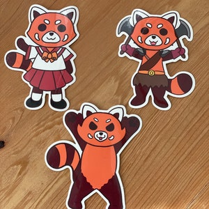 May include: Three red panda stickers with different designs. One is wearing a school uniform, another is a warrior with axes, and the third is raising its arms in the air.