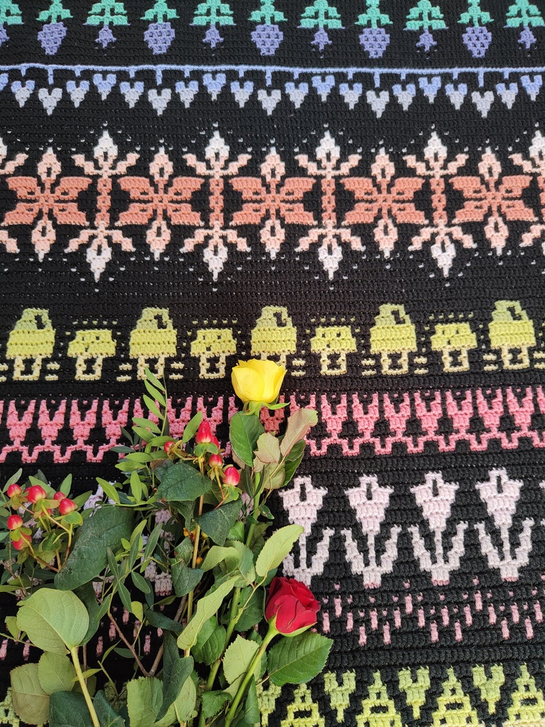 K&ouml;nnte beinhalten: Ein Strau&szlig; gelber und roter Rosen mit gr&uuml;nen Bl&auml;ttern auf einer schwarz-wei&szlig;en H&auml;keldecke mit geometrischem Muster.