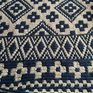 May include: A crocheted throw blanket with a geometric pattern in shades of blue and cream.