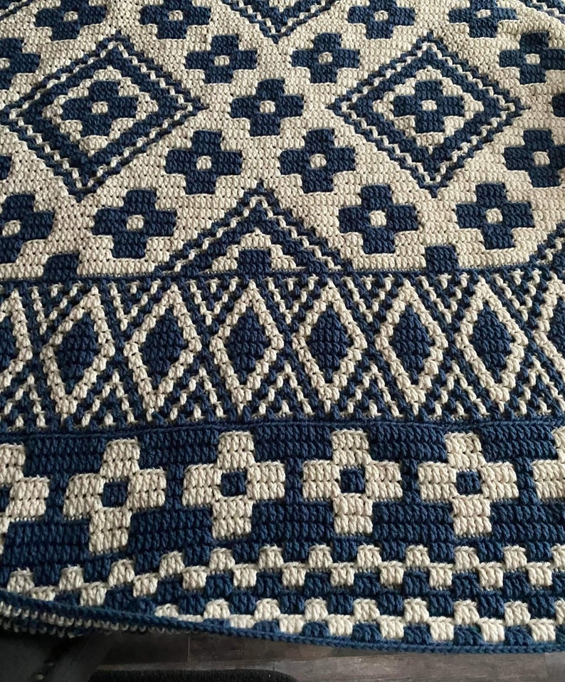 May include: A crocheted throw blanket with a geometric pattern in shades of blue and cream.