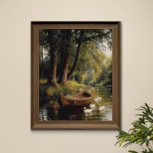 Puede incluir: Una pintura de paisaje enmarcada representa una serena escena fluvial. Una barca de madera descansa cerca de la orilla, con varios patos nadando cerca. Los árboles bordean las orillas del río, y la obra de arte está en un marco de madera marrón.