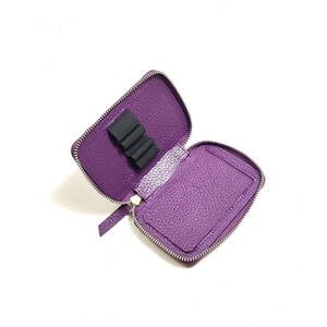 May include: A purple leather zippered pouch with a black elastic band inside for holding pens or pencils.