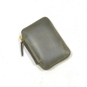 May include: A small, dark green leather wallet with a gold zipper.