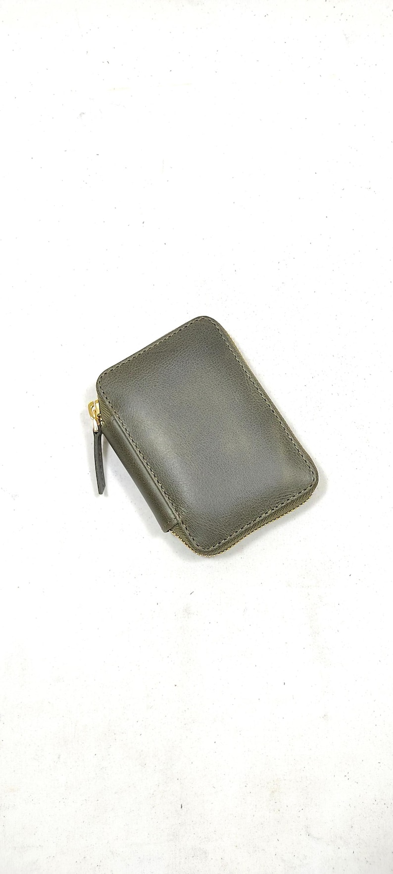 May include: A small, dark green leather wallet with a gold zipper.