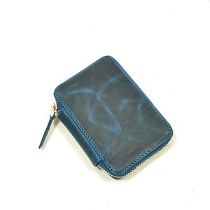 May include: A small, blue leather wallet with a zipper closure. The wallet has a marbled pattern.