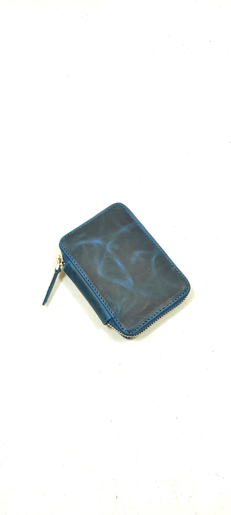 May include: A small, blue leather wallet with a zipper closure. The wallet has a marbled pattern.