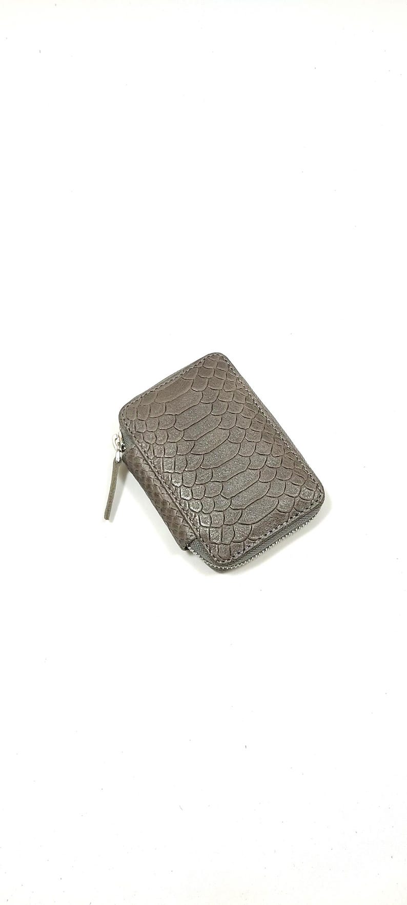 May include: A brown leather wallet with a snakeskin pattern and a zipper closure.