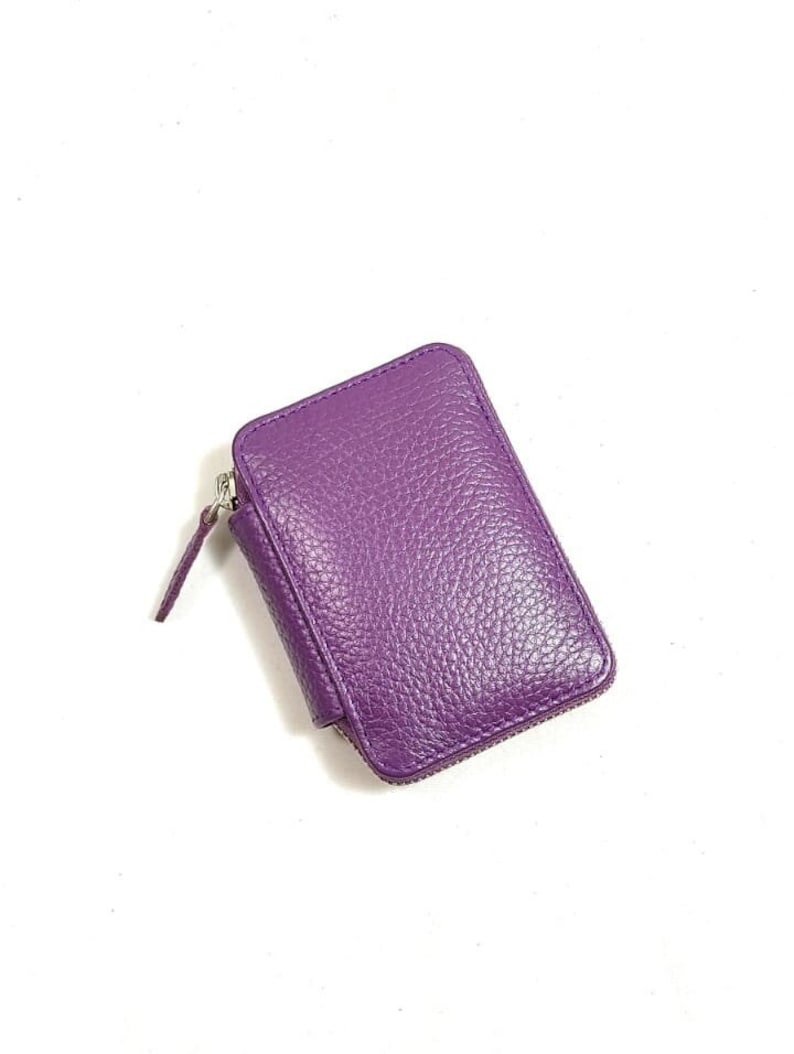 May include: A small purple leather zippered wallet.