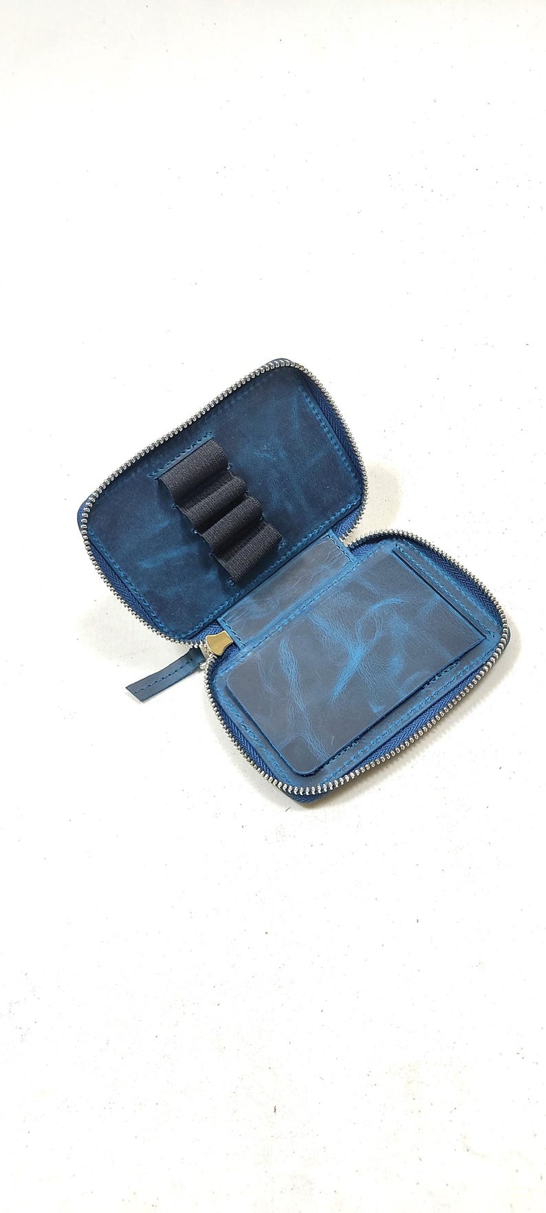 May include: A blue leather zippered pouch with a pen holder and a separate pocket. The pouch is open and the zipper is partially unzipped.