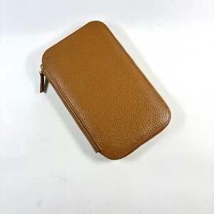 May include: A rectangular, brown leather wallet with a zipper closure. The wallet has a textured surface and a rounded top. The zipper pull is a darker shade of brown.
