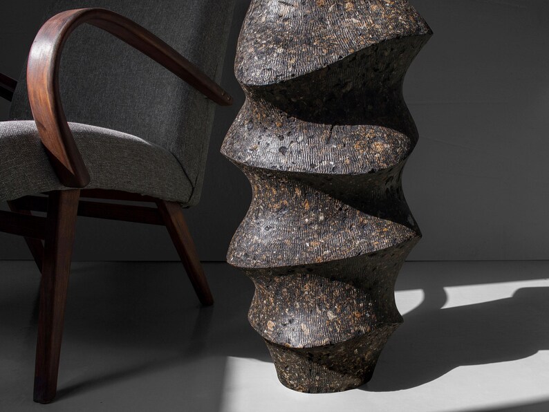 May include: A dark gray ceramic vase with a unique, twisted, and textured design. The vase has a rough, uneven surface and a spiral shape.