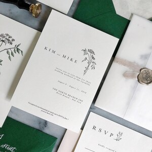 May include: A wedding invitation suite with a green envelope, a white RSVP card, and a white invitation card with the text "KIM and MIKE" and a floral illustration. The invitation card also includes the text "invite you to join them for their wedding weekend in the Catskills August 9 - August 11, 2019 THE NORTH BRANCH INN North Branch, New York Visit population.com/kimandmike for details and to RSVP by June 1!"