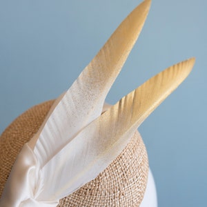 Goldie Beautiful Bridal Headpiece featuring gold tipped feathers and silk tie on a natural straw button base image 6