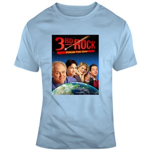 May include: A light blue t-shirt with a graphic of the cast of the television show "3rd Rock From The Sun". The graphic features the show's title in red and a picture of the four main characters standing in front of a depiction of Earth.