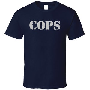 May include: A navy blue t-shirt with the word "COPS" printed in white on the front.