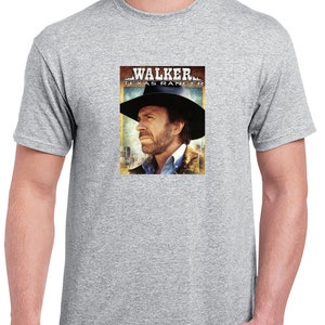 May include: A heather grey t-shirt with a graphic print of Chuck Norris as Walker, Texas Ranger. The graphic is a close-up of his face and features the show's title.