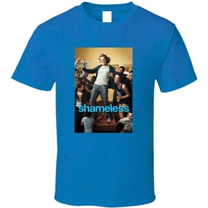 May include: A royal blue t-shirt with a graphic from the TV show "Shameless." The graphic depicts a group of people and the show's title in blue text. The t-shirt is a solid blue colour.