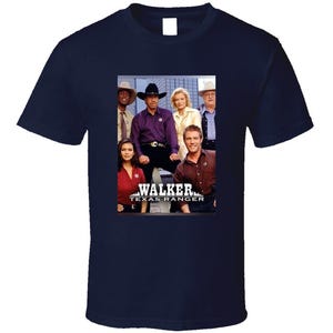 May include: A navy blue t-shirt with a photo of the cast of the TV show "Walker, Texas Ranger". The photo shows the main character, Chuck Norris, and other cast members. The text "Walker, Texas Ranger" is printed below the photo.
