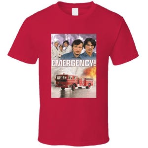 Peut inclure: Un t-shirt rouge avec un graphisme de la série télévisée "Emergency!". Le graphisme comprend des images des acteurs, un camion de pompiers et le mot "EMERGENCY!" en blanc. Le t-shirt est de couleur rouge uni.