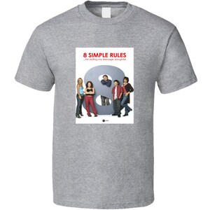 May include: A gray t-shirt with a white graphic of the cast of the television show "8 Simple Rules" standing in front of a large number eight. The text "8 Simple Rules - for dating my teenage daughter" is printed above the image.