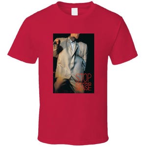 May include: Red t-shirt with a white and light gray image of a man in a suit. The text "STOP MAKING SENSE" is printed in red on the image.