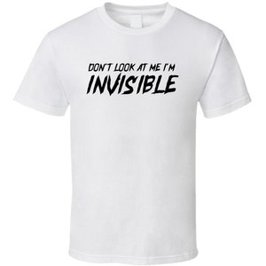 May include: White t-shirt with the text "DON'T LOOK AT ME I'M INVISIBLE" in black, stylized lettering. The shirt has a crew neck and short sleeves. The text is centered on the front of the shirt.