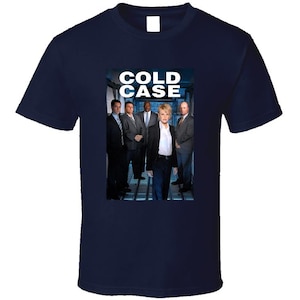 May include: Navy blue t-shirt featuring the text "COLD CASE" above a group of people in suits. The image on the shirt appears to be a promotional image for the television show.