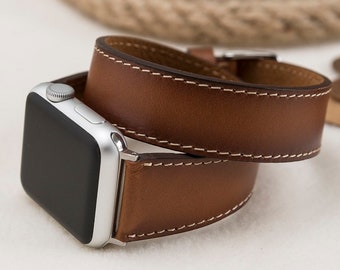 May include: A brown leather Apple Watch band with white stitching. The band is double wrapped around the watch.