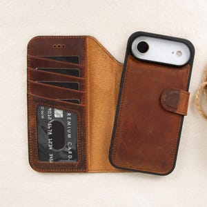 May include: Brown leather phone case with a wallet design. The case has slots for cards and a magnetic closure. The phone case is shown open and closed, displaying the interior and exterior details. The phone case is designed to fit a smartphone.