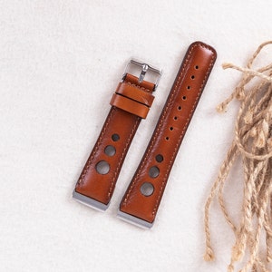 May include: Two brown leather watch straps with silver buckles. One strap has a perforated design and the other has a smooth surface.
