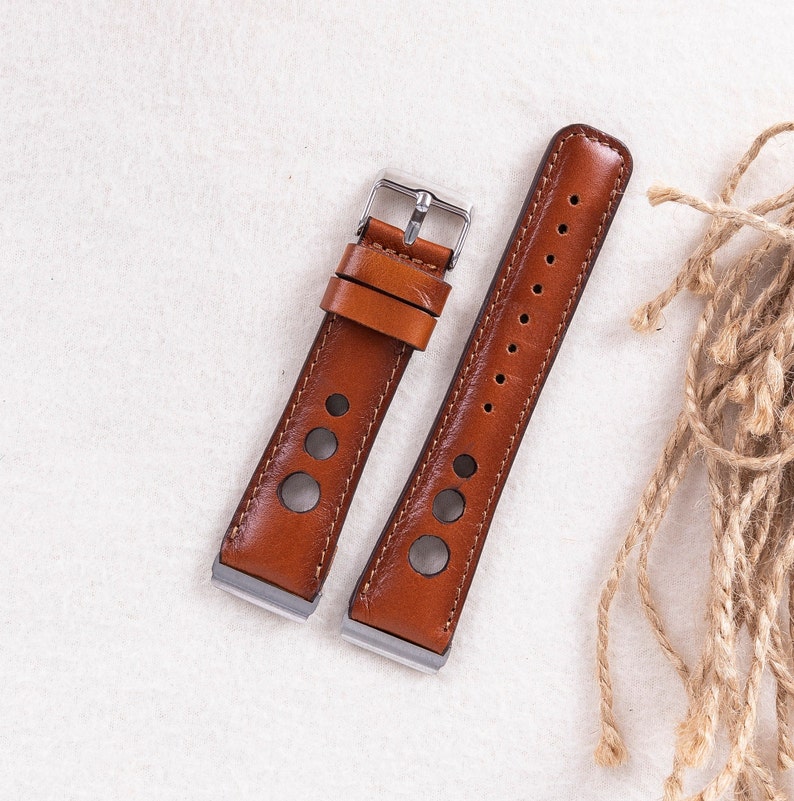 May include: Two brown leather watch straps with silver buckles. One strap has a perforated design and the other has a smooth surface.