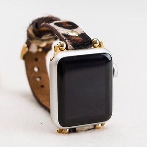 May include: A silver Apple Watch with a black screen and a brown and white leopard print leather band with gold accents.