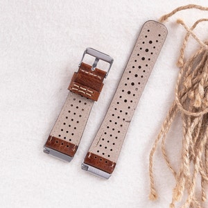 May include: Two brown leather watch straps with white stitching and a perforated design. The straps have silver buckles.