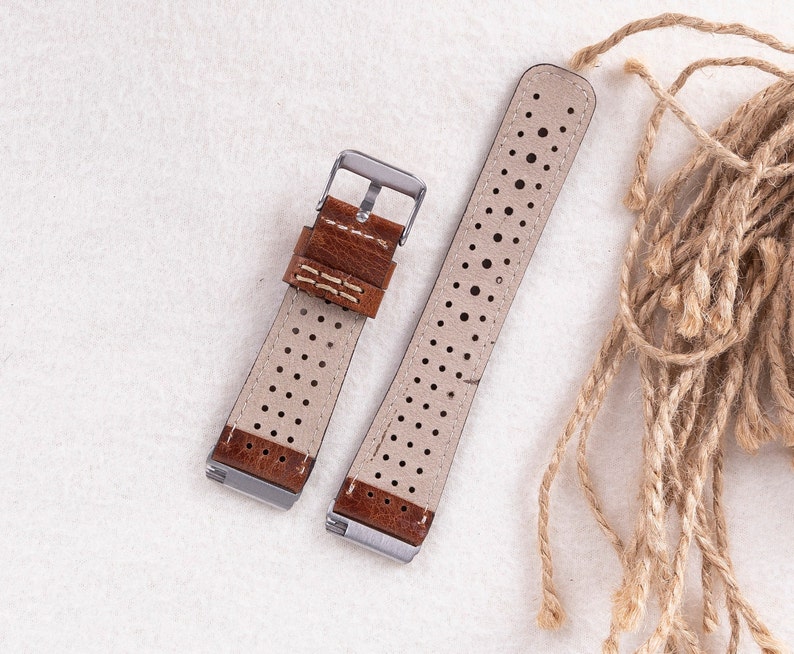 May include: Two brown leather watch straps with white stitching and a perforated design. The straps have silver buckles.