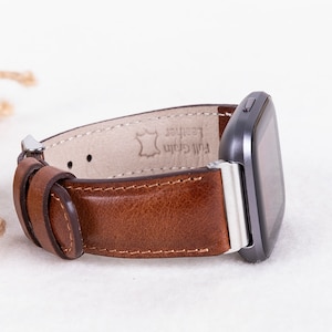 May include: A brown leather watch band with silver hardware and the text "Full Grain Leather" on the inside.