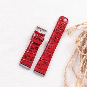 May include: Two red leather watch straps with a crocodile pattern. The straps have silver buckles.