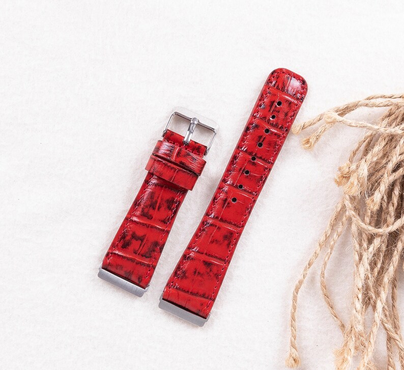May include: Two red leather watch straps with a crocodile pattern. The straps have silver buckles.