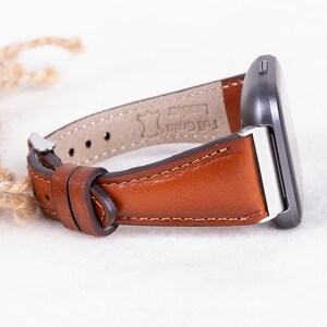 May include: A brown leather watch strap with a silver buckle and the text "Full Grain Leather" on the underside.