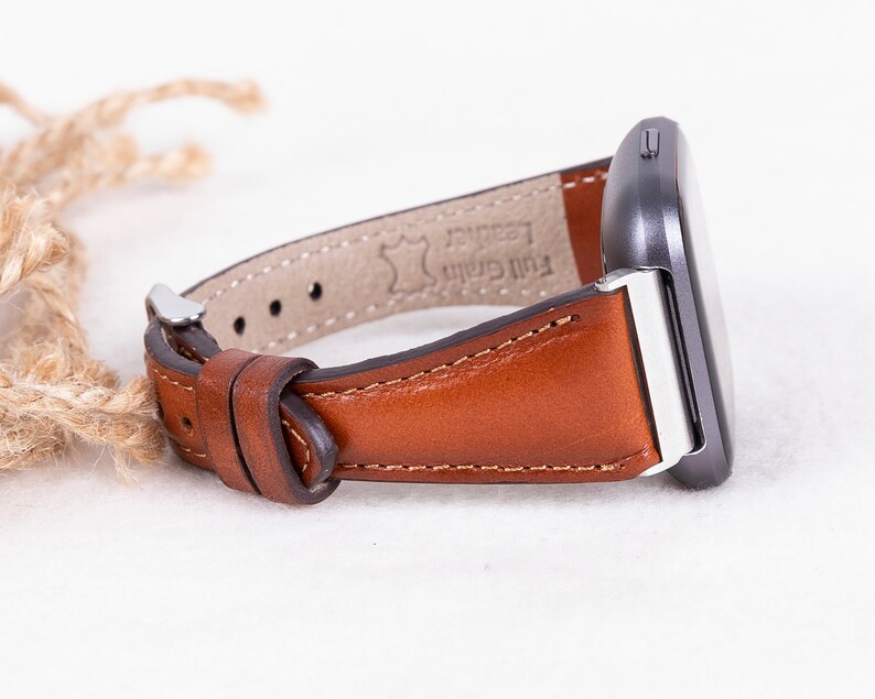 May include: A brown leather watch strap with a silver buckle and the text "Full Grain Leather" on the underside.