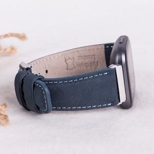 May include: A dark blue leather watch band with white stitching and a silver buckle. The band is labeled "Full Grain Leather".