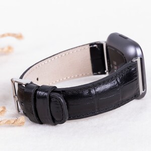 May include: Black leather watch band with a silver buckle and a silver watch face.