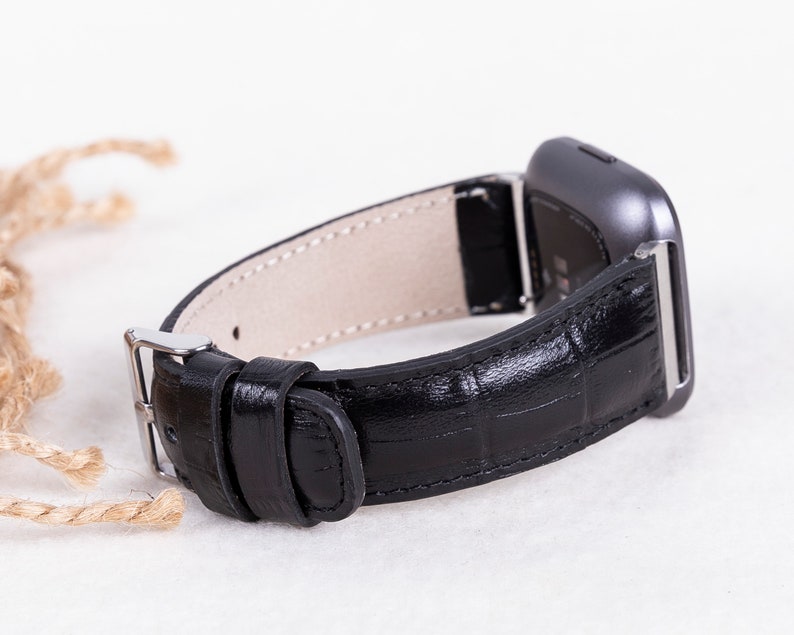 May include: Black leather watch band with a silver buckle and a silver watch face.