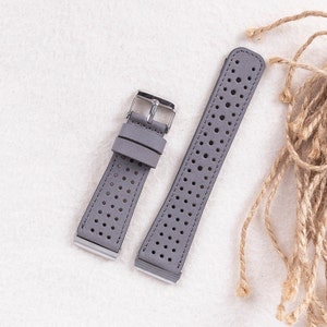Puede incluir: Dos correas de reloj de cuero gris con un dise&ntilde;o perforado. Las correas tienen hebillas plateadas.