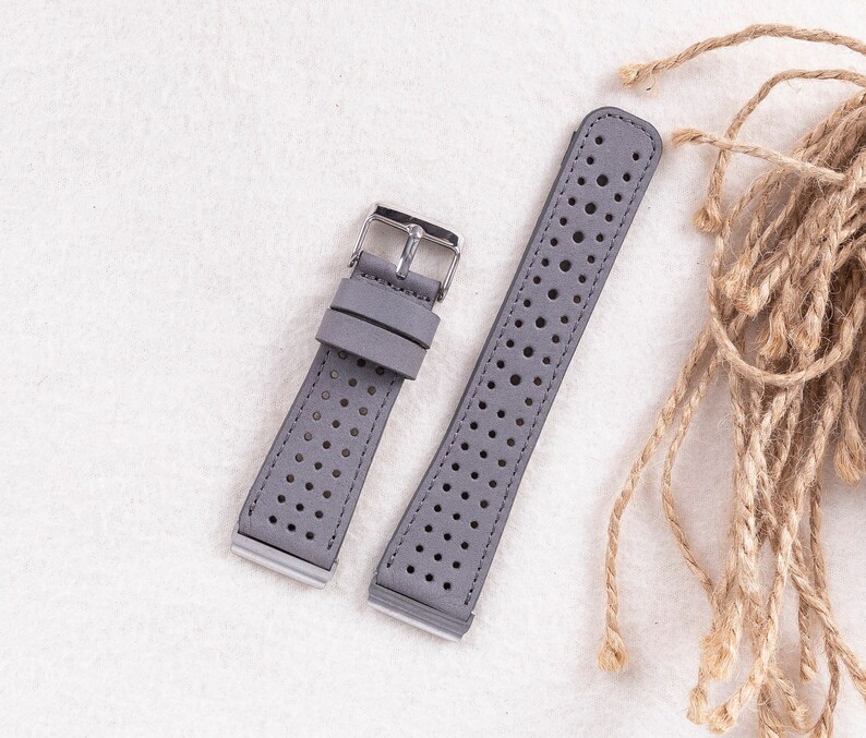 Puede incluir: Dos correas de reloj de cuero gris con un dise&ntilde;o perforado. Las correas tienen hebillas plateadas.