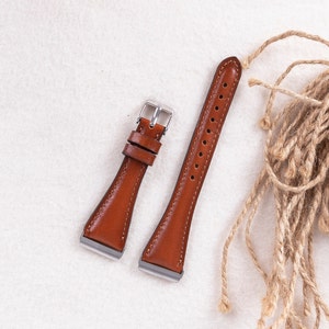 May include: Two brown leather watch straps with silver buckles. The straps are on a white surface.